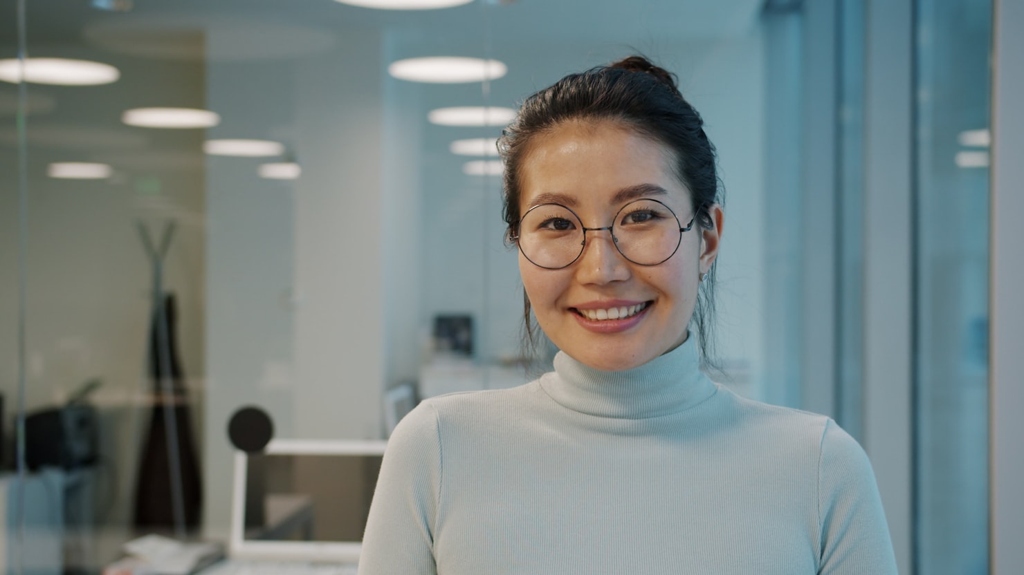 眼鏡をかけた女性がオフィスで立つ