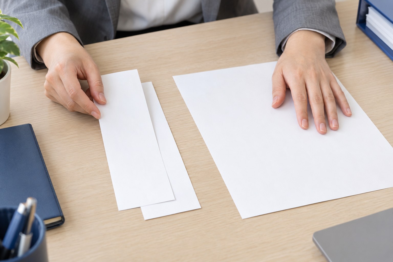 執務室の机で、細長い票の用紙2枚を重ね、申告書の用紙を押さえる手