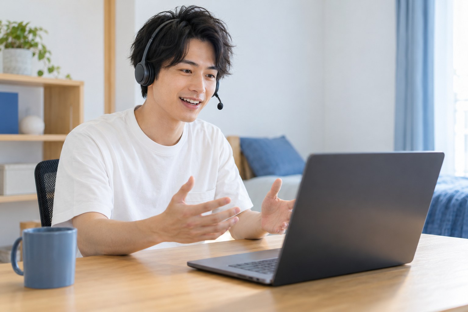 午前の自宅で、ヘッドセットを着けてビデオ会議で同僚と笑って話す会社員