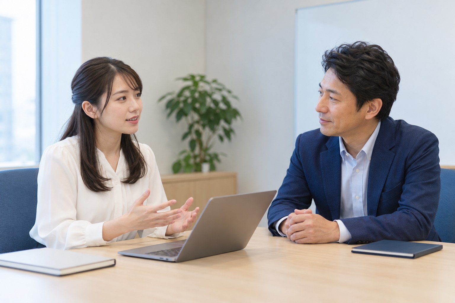 午後の会議室で、上司に出社日を増やしたいと相談する会社員