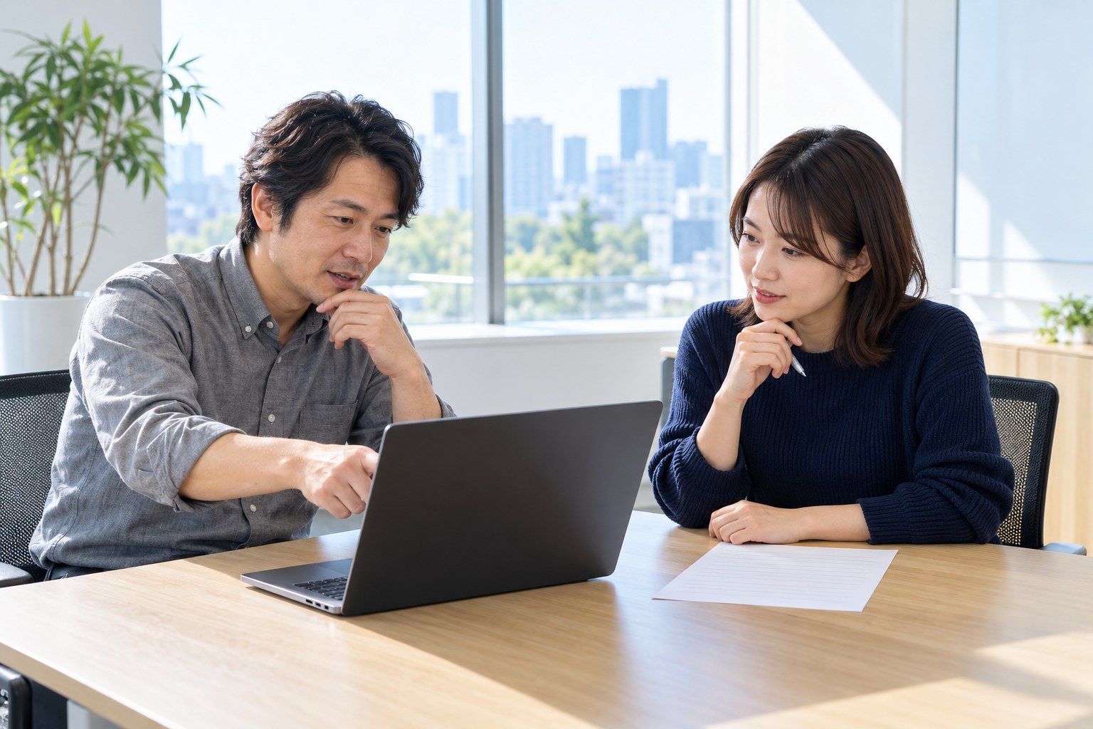 午後の会議室で、職務経歴書とノートパソコンを見比べる採用担当のエンジニア2人